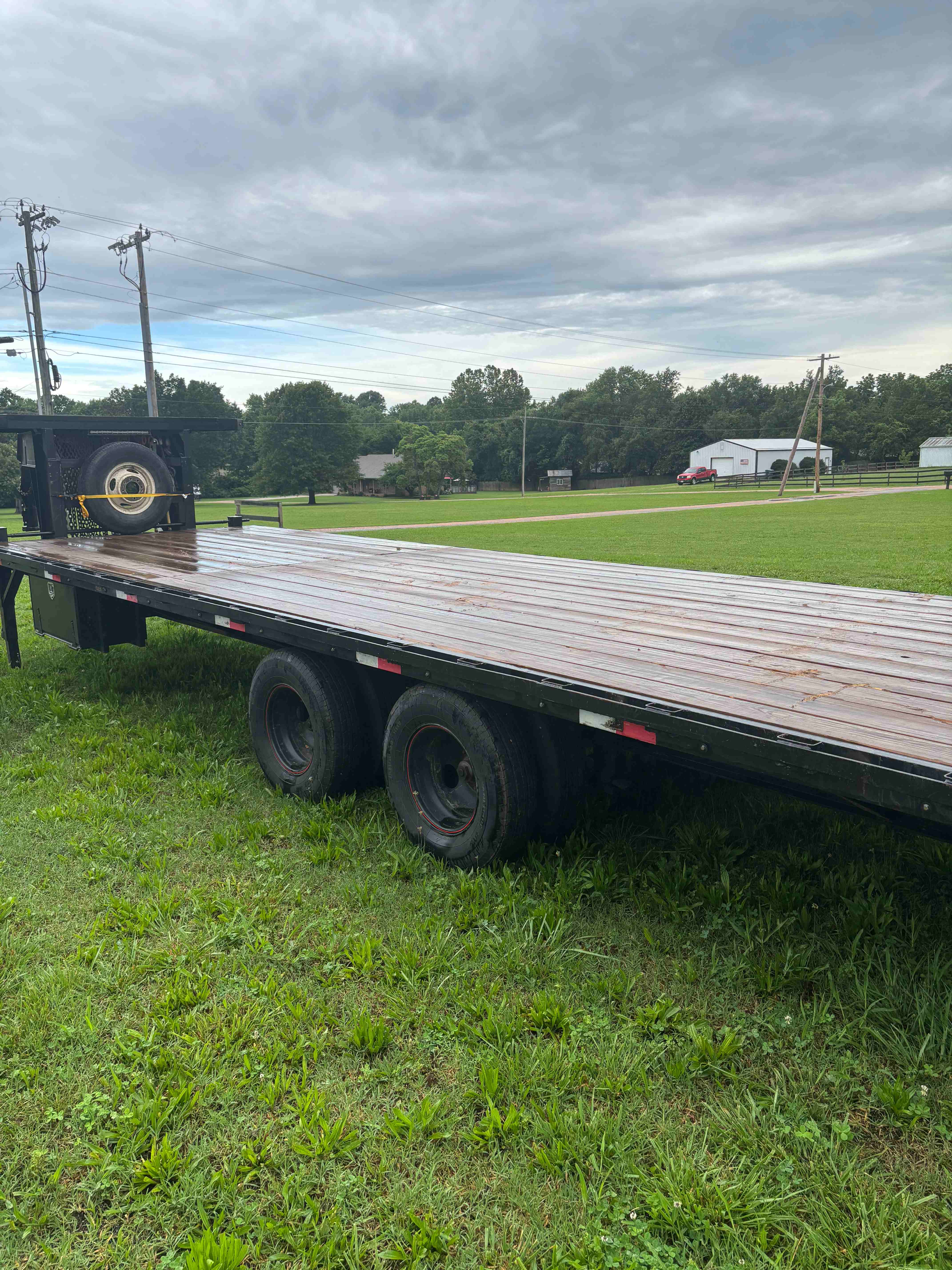 Gooseneck trailer side view showing triple axles and wood deck - Southwest Missouri